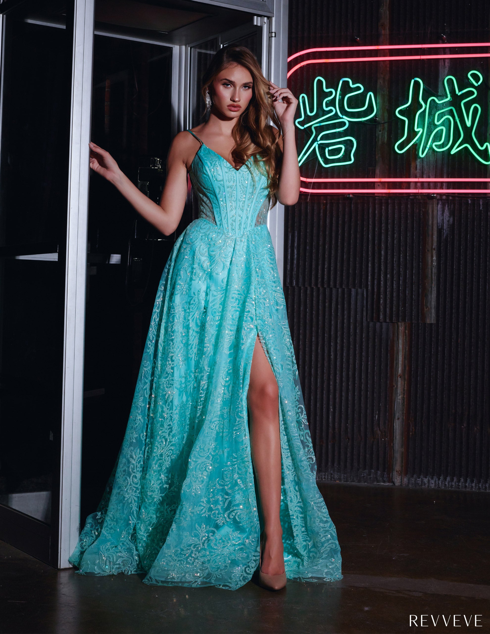 Woman with long brown hair wearing a mint green lace gown with a thigh-high slit, posing near a neon sign with Chinese characters.